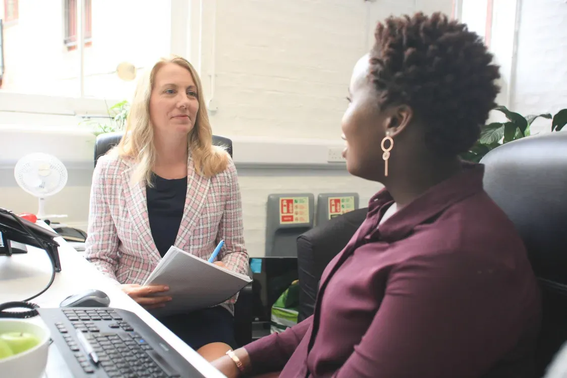 An ergonomics consultant listening to a person at their workstation