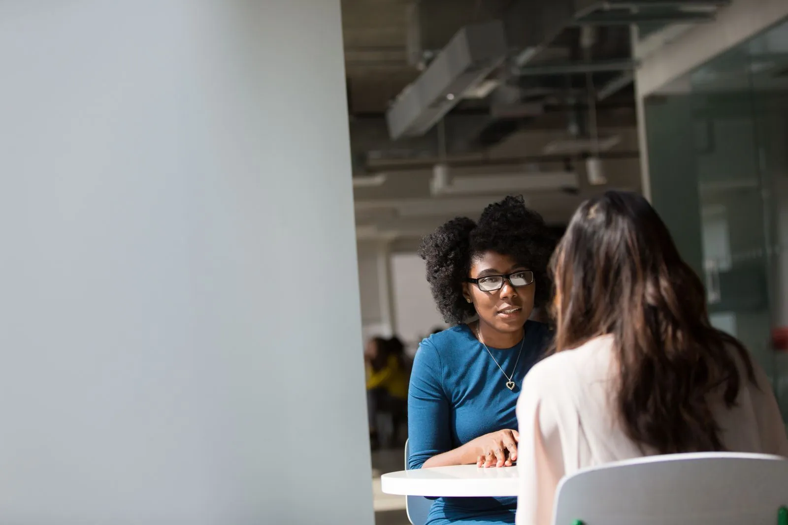 Two women chatting across a table in a shared office