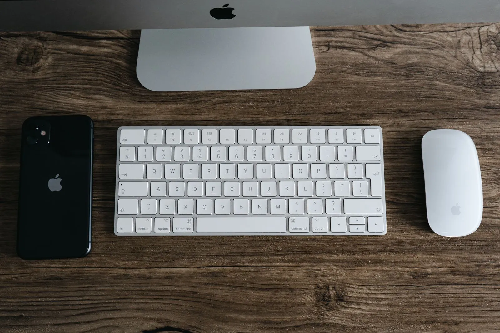 A compact keyboard and mouse on a wooden desk