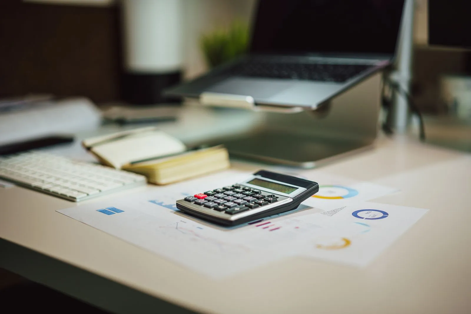A calculator, keyboard and financial charts on a desk