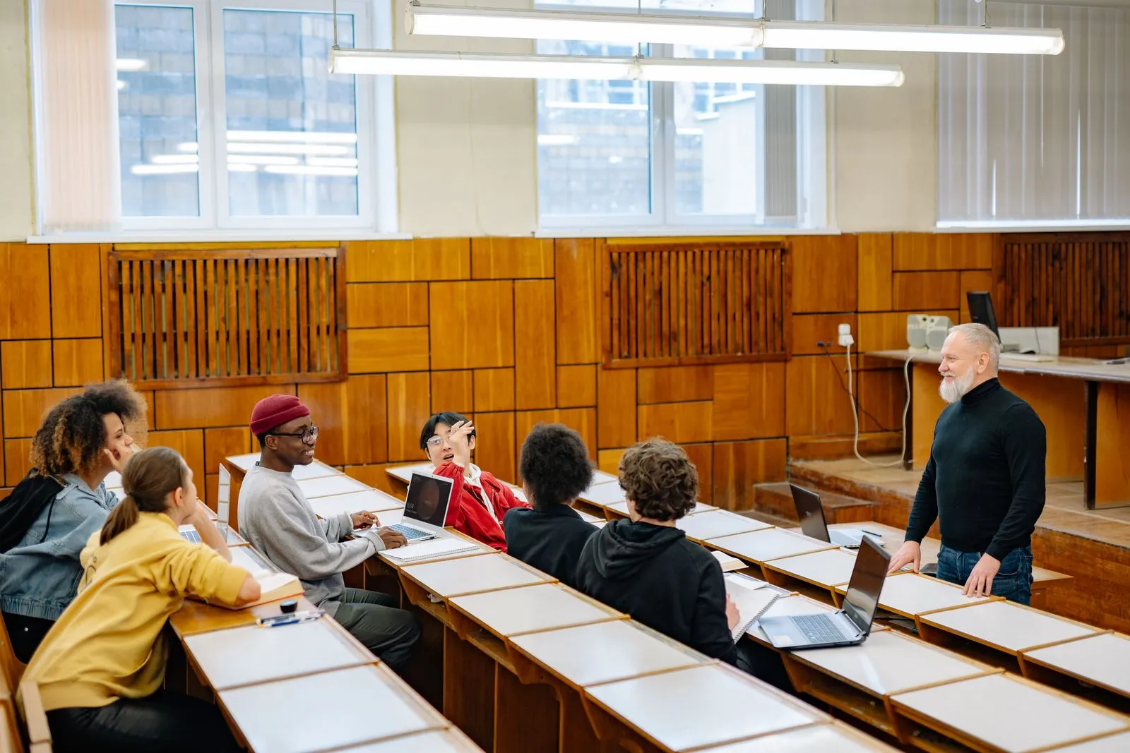 A lecturer and students discussing coursework in a lecture room