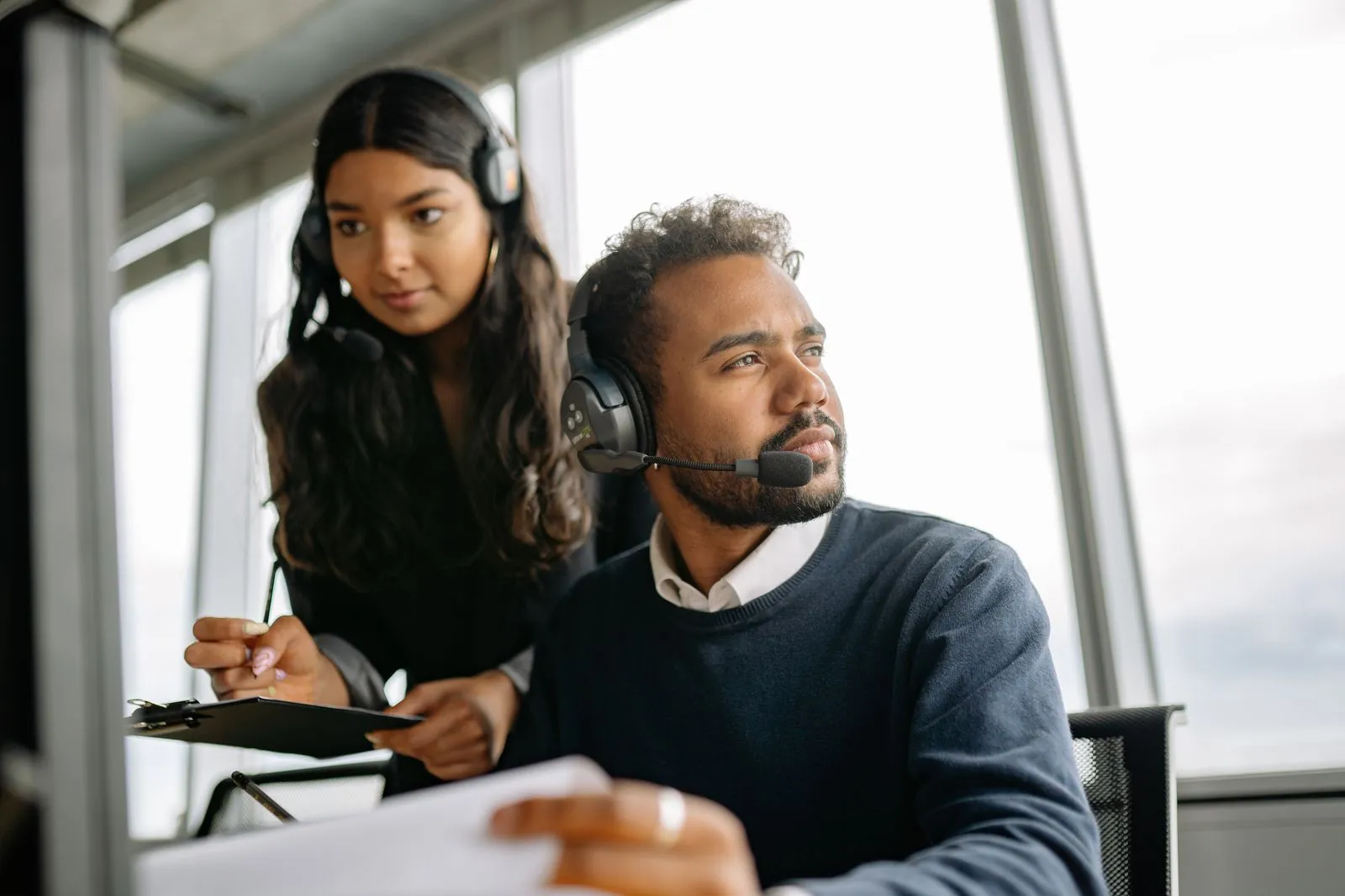 Two colleagues using headsets at an office workstation